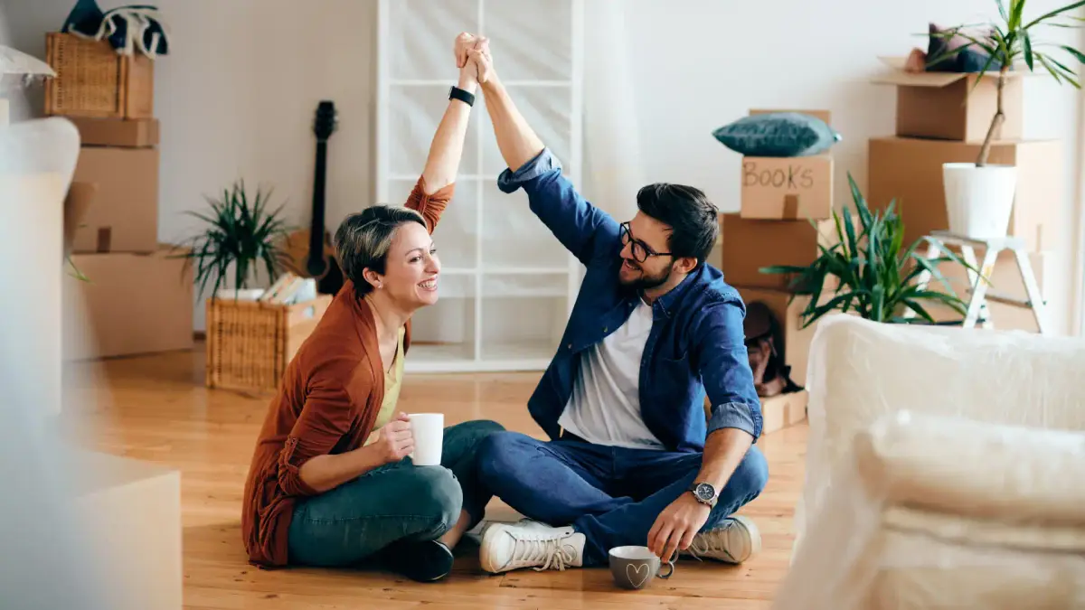 a couple sitting on the floor in a living room and smiling