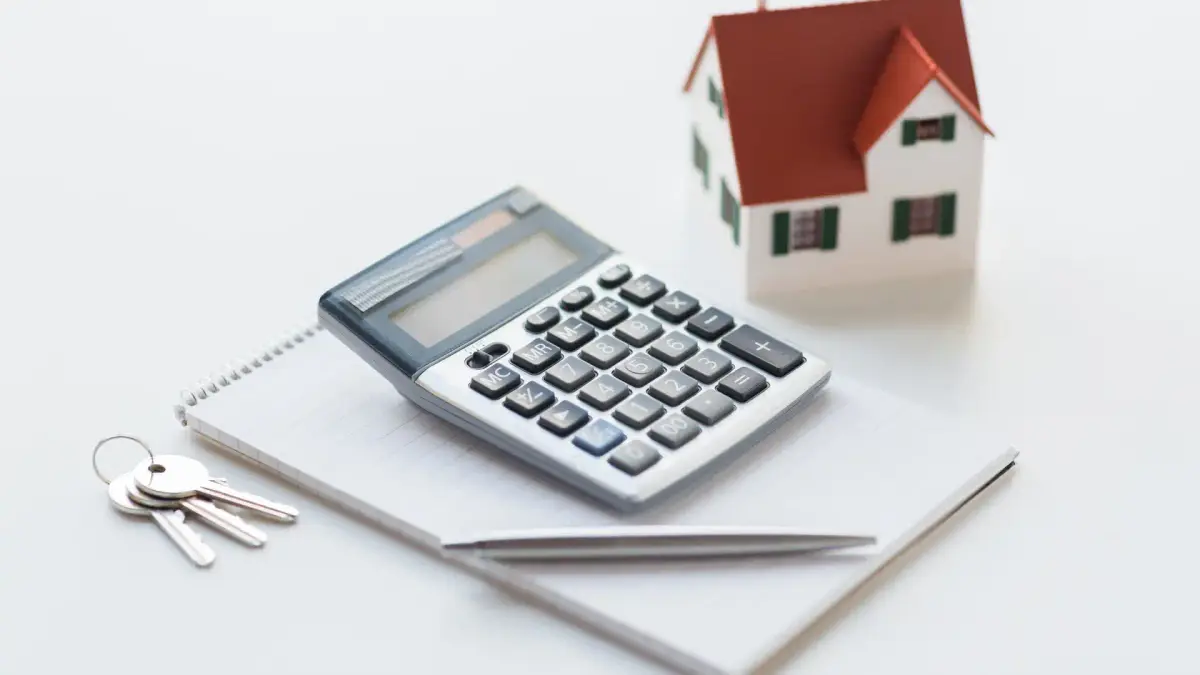 calculator with pen, model home, notepad and keys on the side