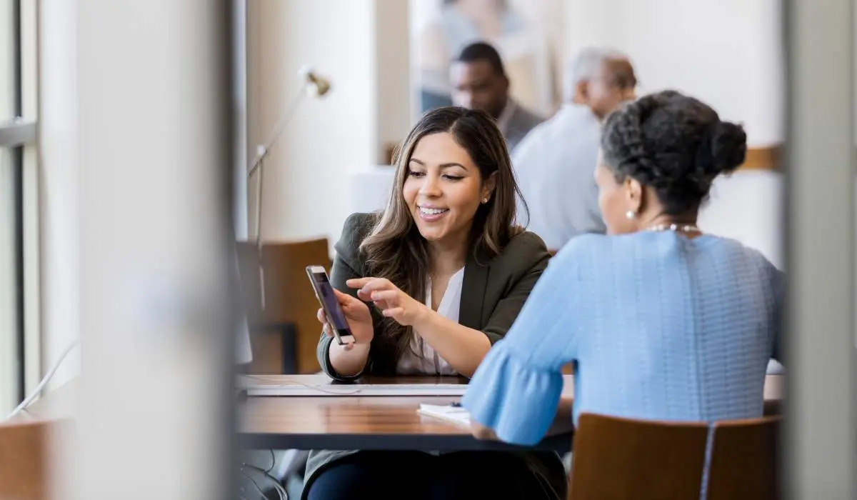 person showing something on phone to another person in a professional setting 