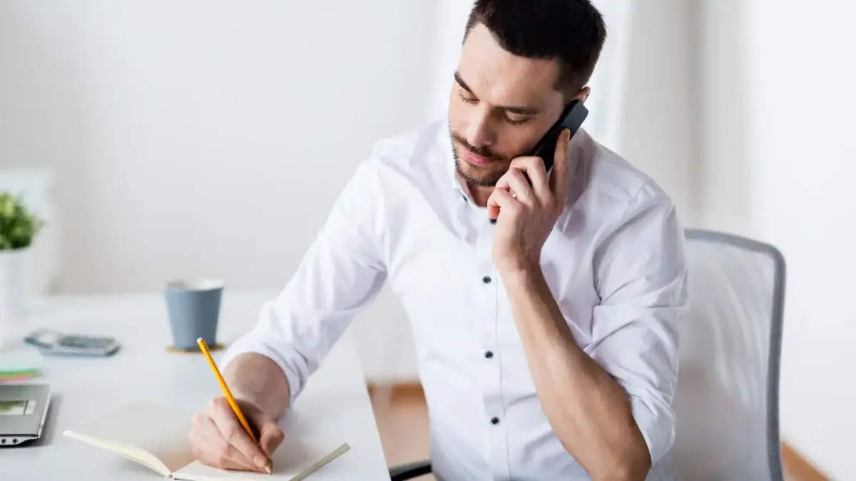 a person sitting at a desk talking on the phone