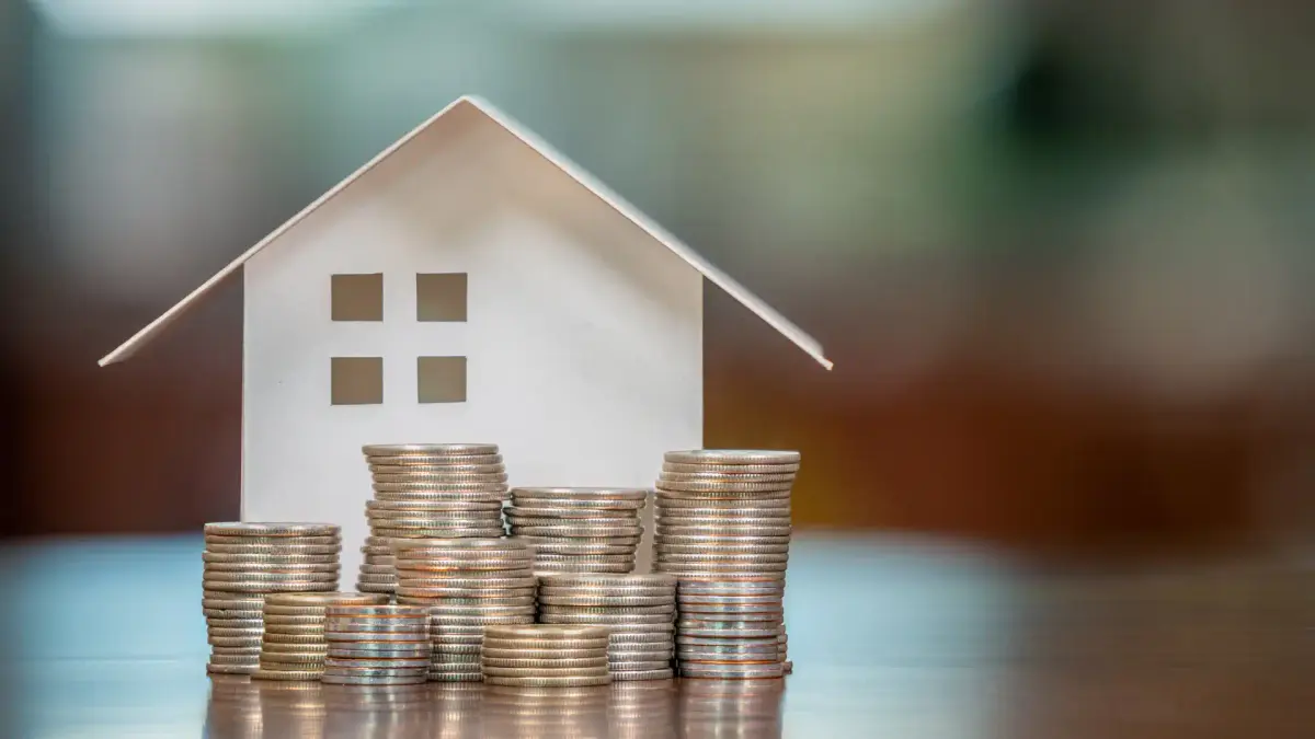 house model with coins stacked in front of it